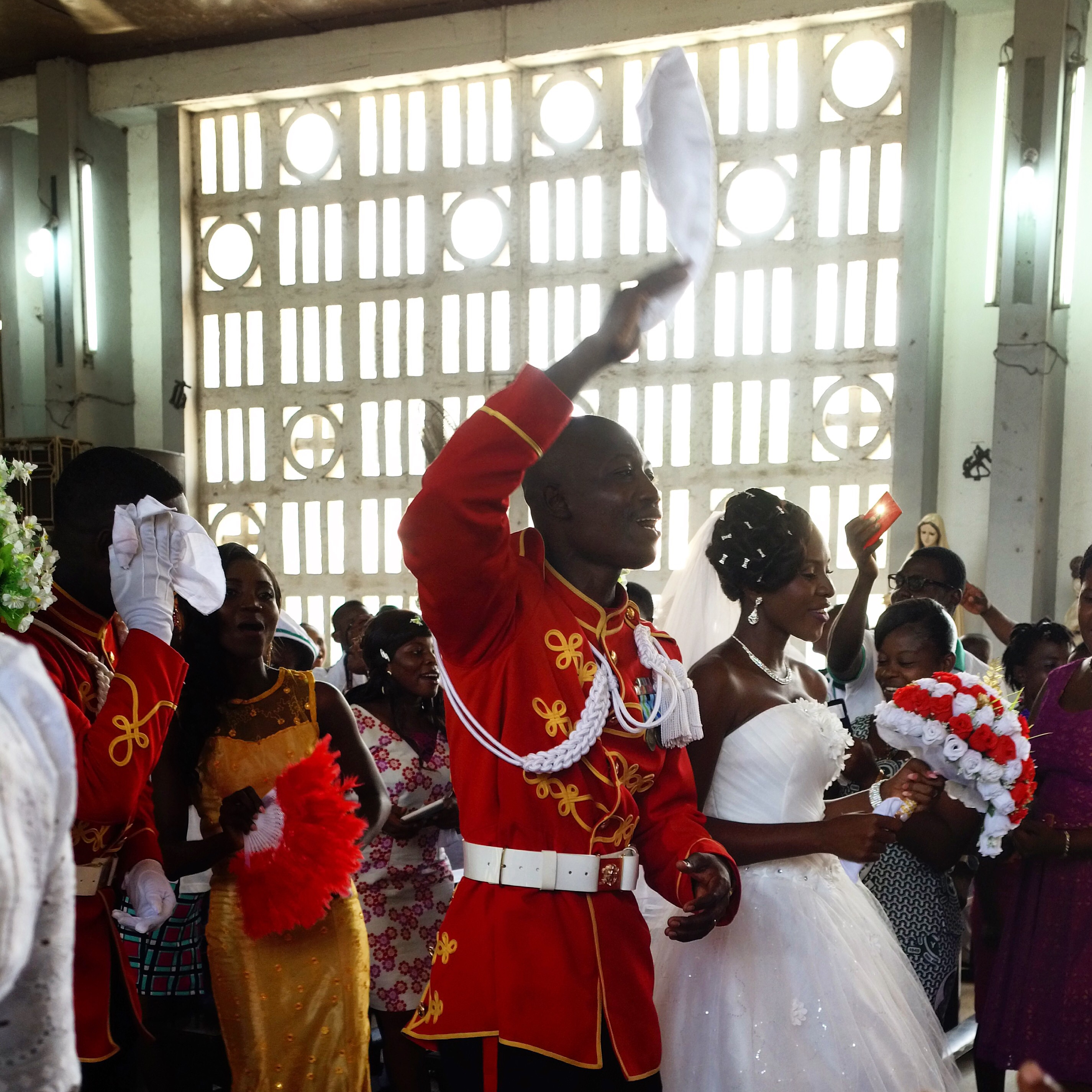 a man in a red military jacked and a woman in a white wedding dress walking down the aisle