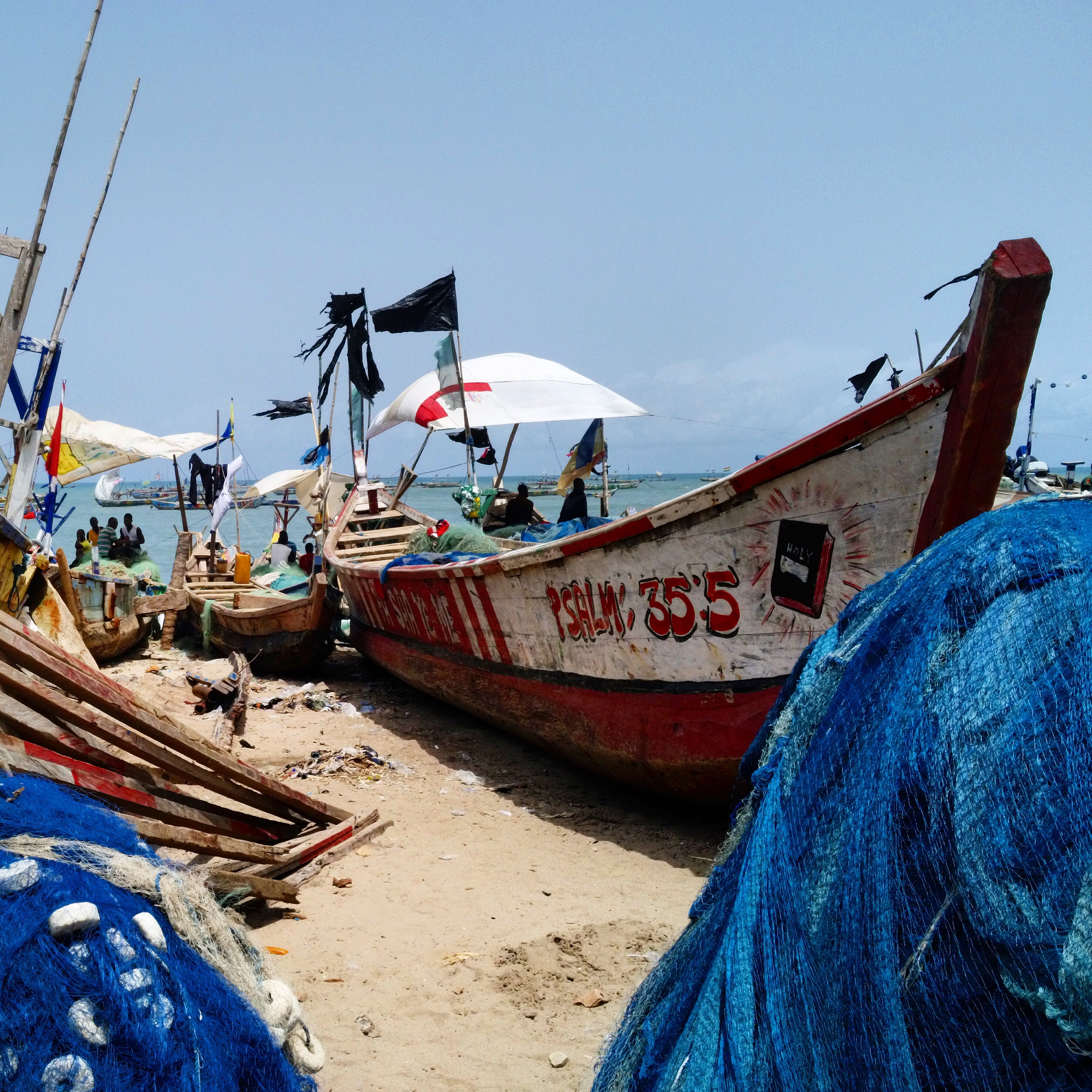 a beached wooden boat with psalm 35:5 painted on the side with other boats surrounding it in front of the ocean