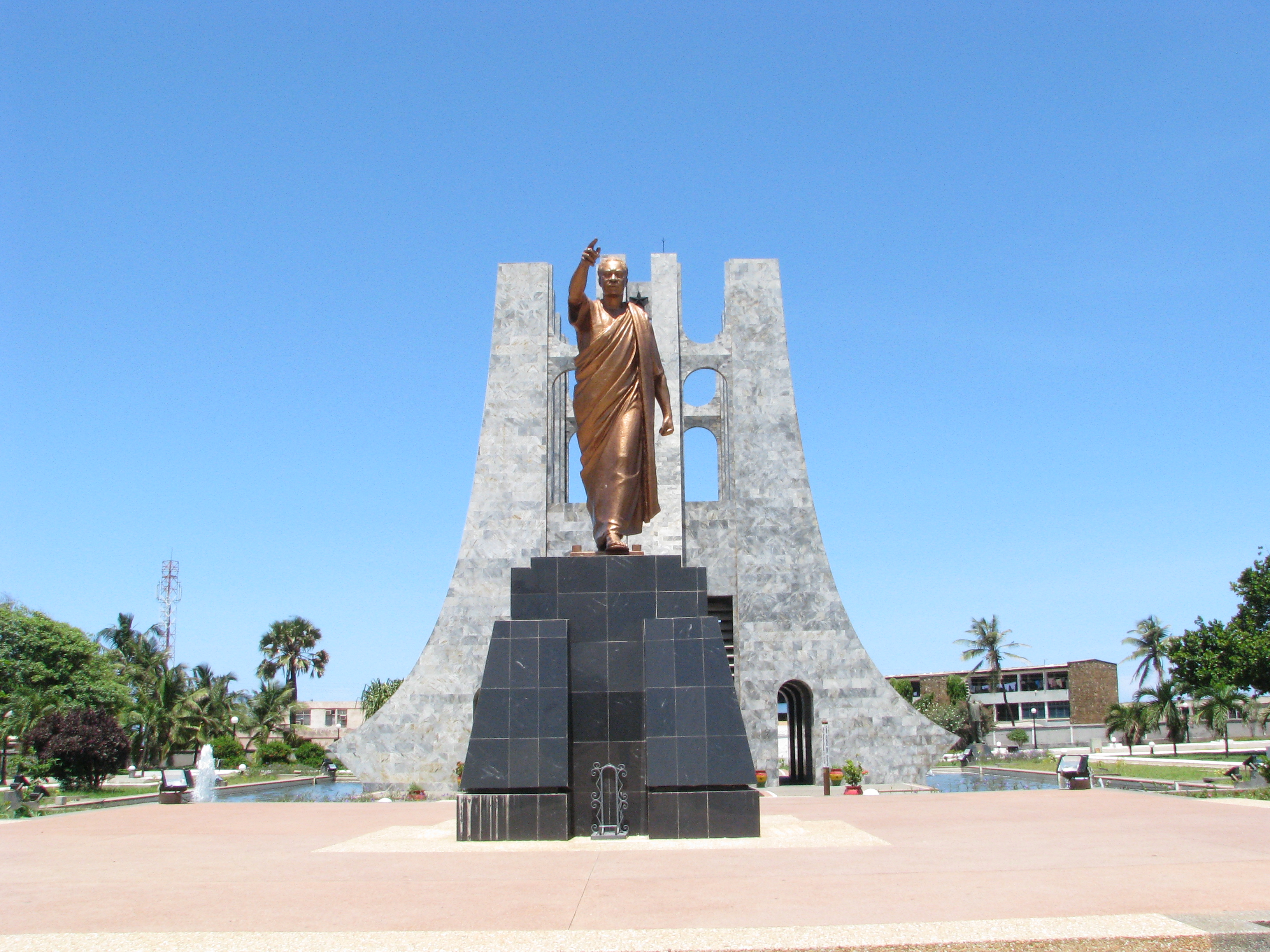 A gold colored statue of Kwame Nkrumah with his arm raised pointing forward