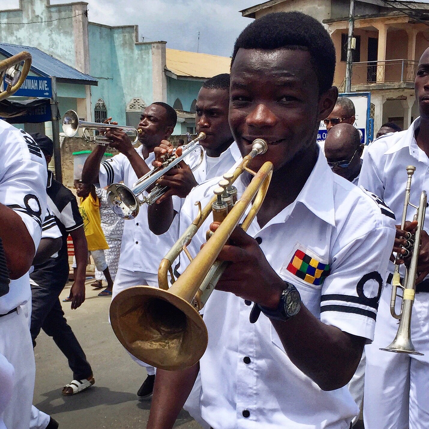 a young man in a marching band playing the trumpet and looking at the camera