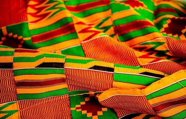 A piece of woven cloth, with bold, graphic patterns in yellow, green, red and black.